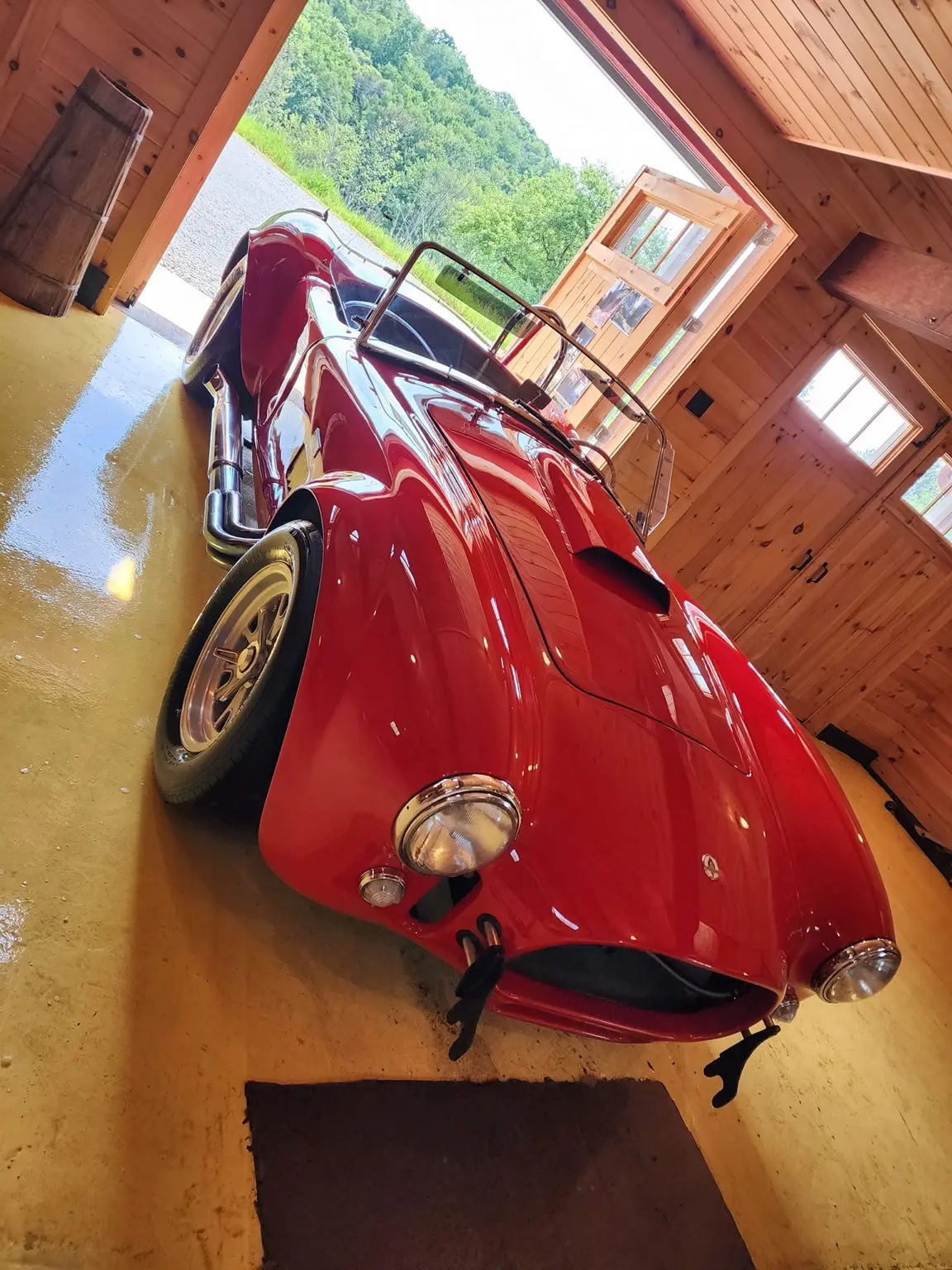 Glossy red classic convertible roadster inside a wood-paneled garage